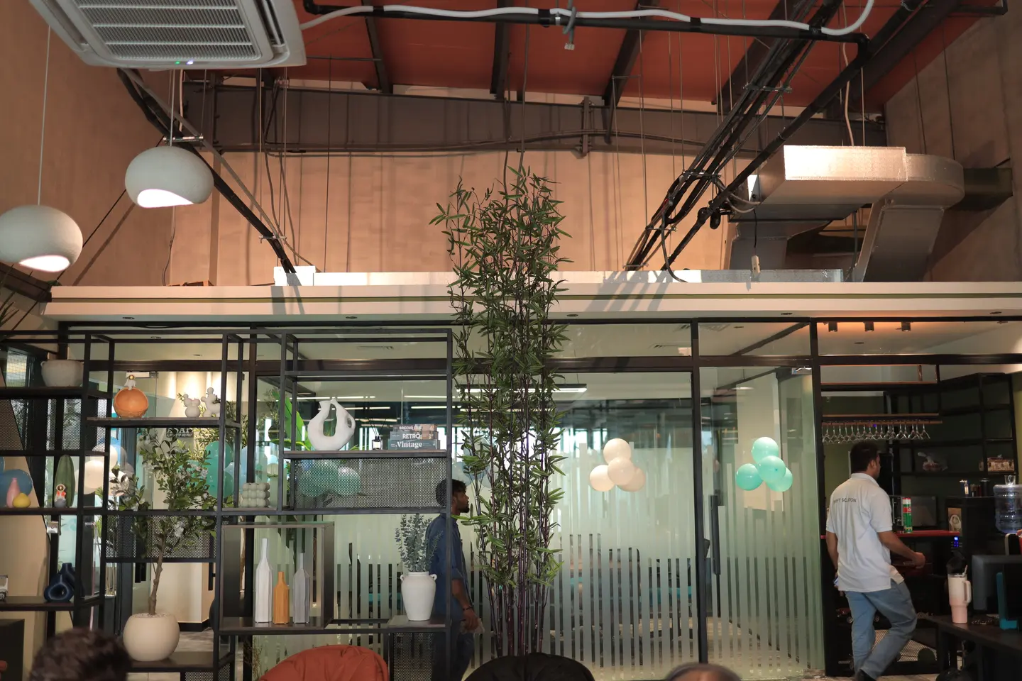 An open office interior with plants, glass partitions and high ceilings.