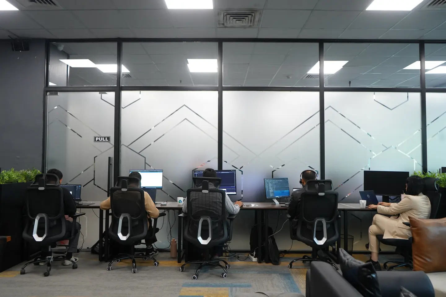 A dedicated production room: a row of workstations behind a glass wall.